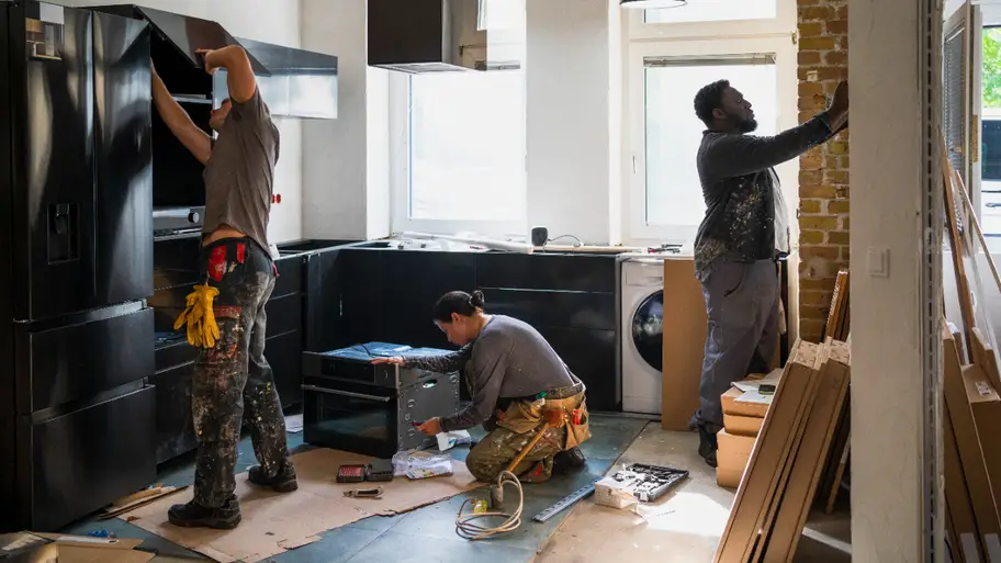 Workers renovating a modern kitchen space.